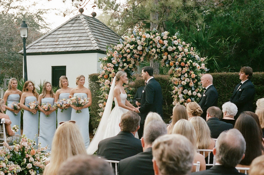 Perra and Ryan's elegant outdoor wedding ceremony at Rosemary Beach, Florida, featuring a romantic floral arch, pastel bridesmaid dresses, and classic coastal wedding style