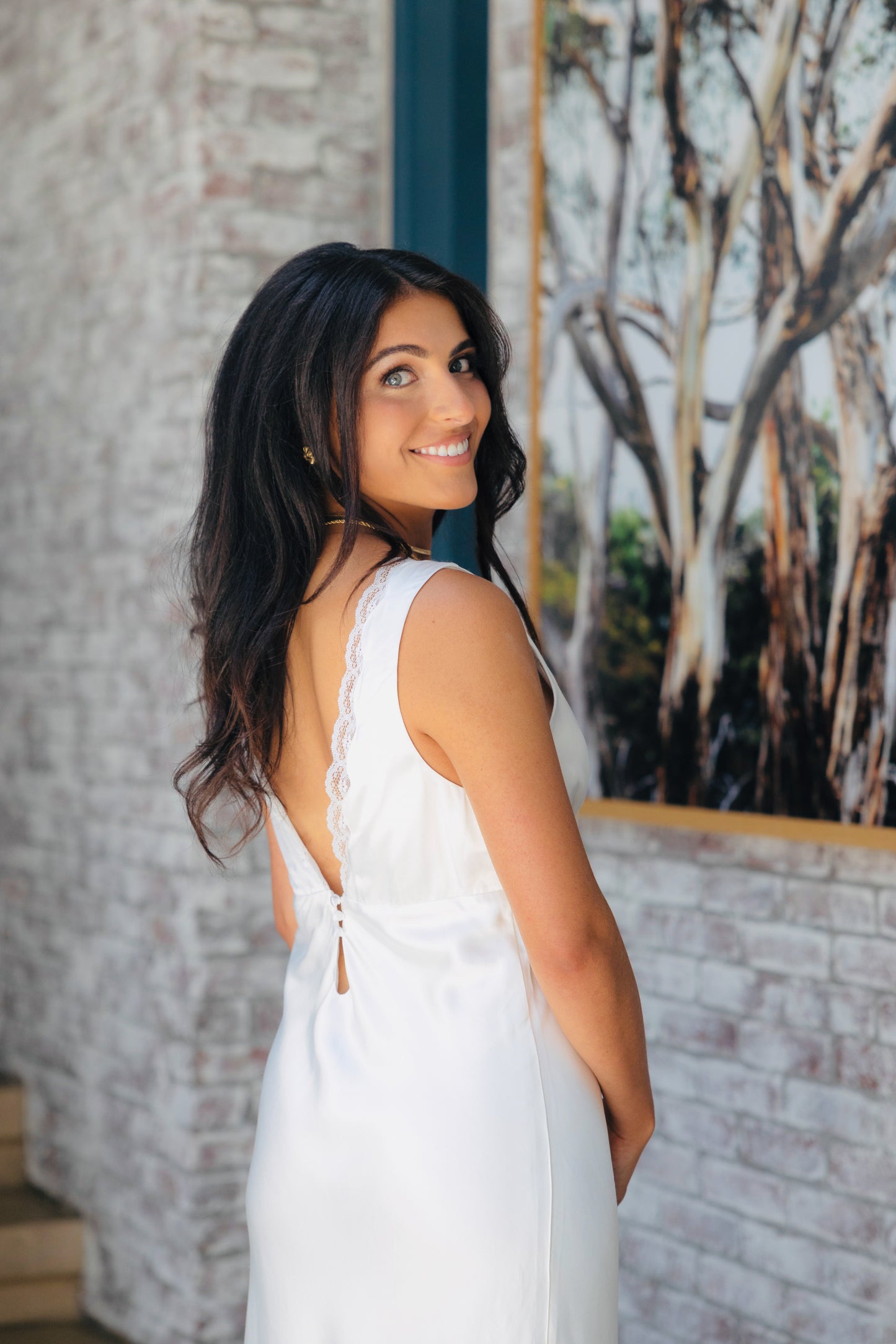 Bride wearing a white slip dress with a deep v-neck back and lace details