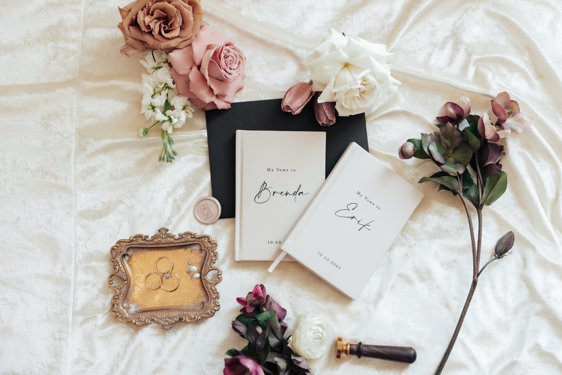a flatlay image of wedding vow books, flowers and wedding rings