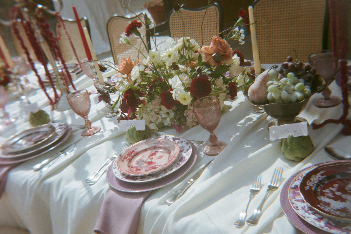 Gorgeous wedding tabelscape with red and peach roses, white table linen, and floral plates