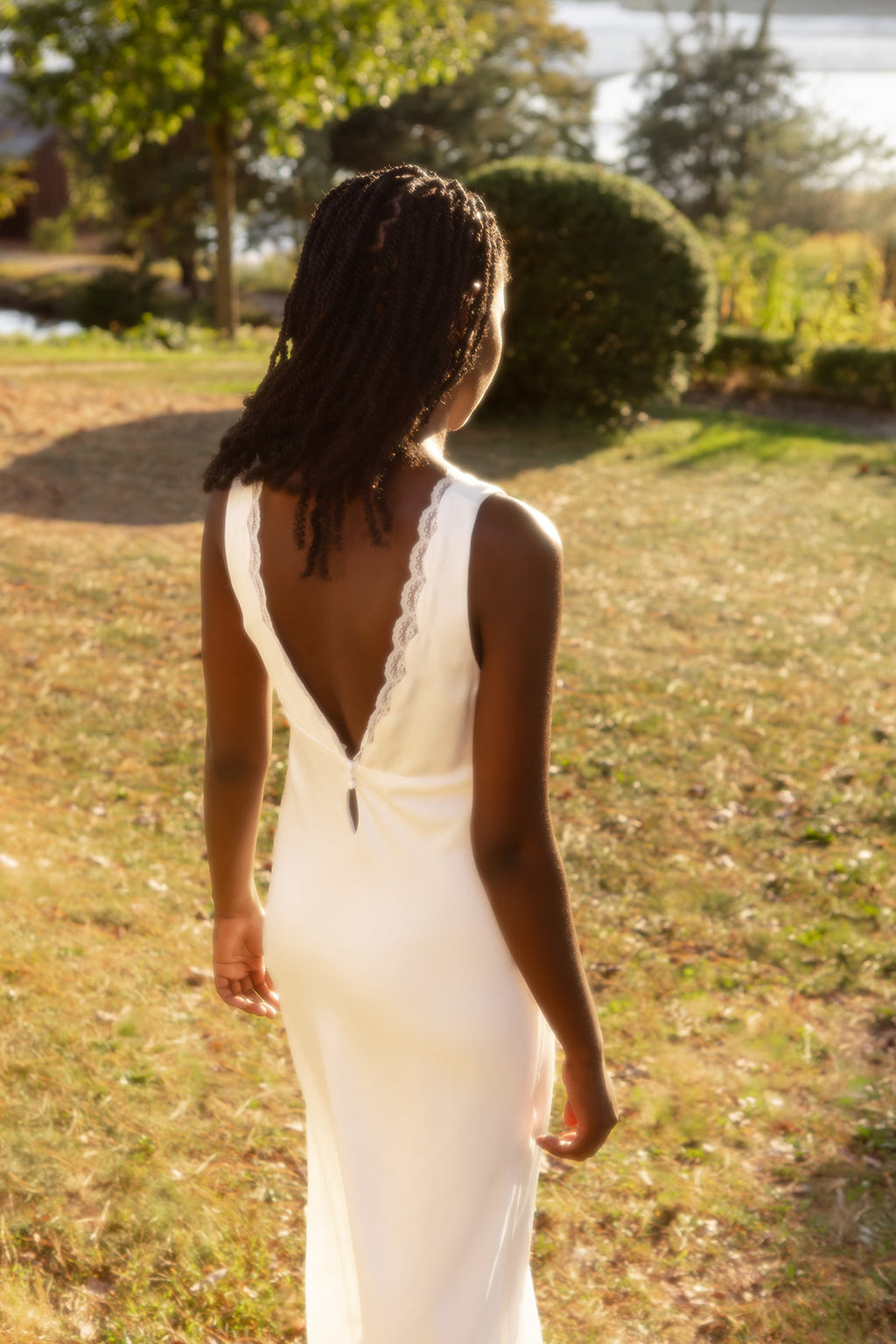 Bride in a white slip dress with lace details walking in a garden
