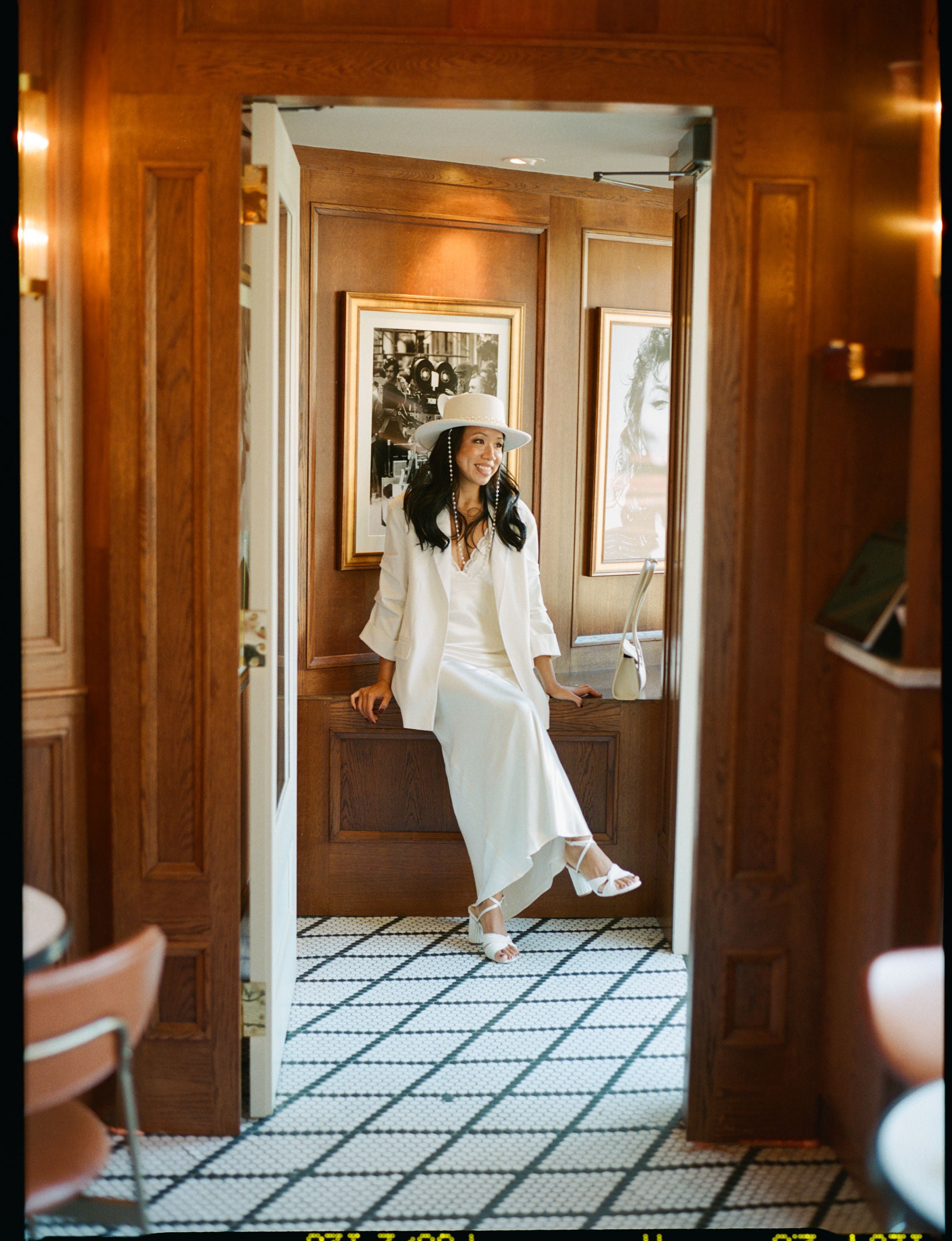 Founder Tiffany Lee McCabe wearing a white bridal slip dress styled with heels, white blazer, and white brim hat. 